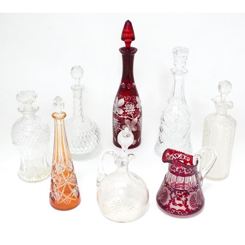 253 - A quantity of assorted cut glass and lead crystal decanters, to include a Bohemian red glass example... 