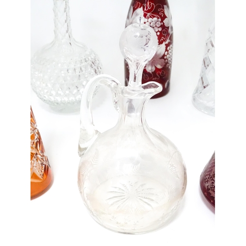 253 - A quantity of assorted cut glass and lead crystal decanters, to include a Bohemian red glass example... 