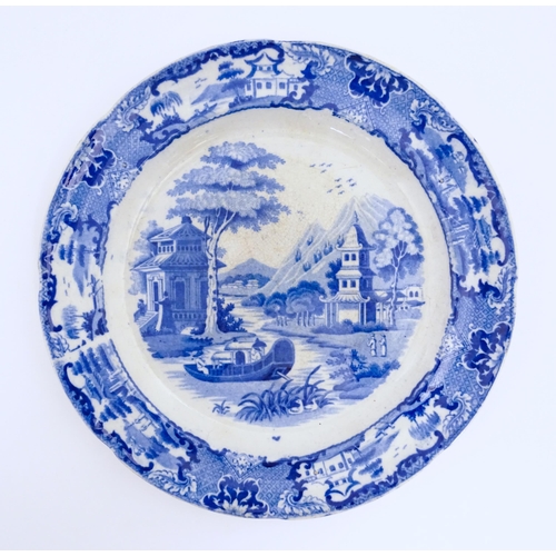 68 - An unusual 19thC blue and white plate decorated with an Oriental river landscape with ornate pagodas... 