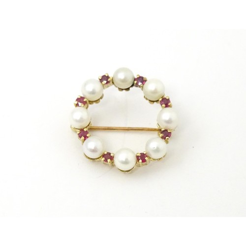 792 - A 9ct gold pendant / brooch of circular set with pearls and round cut rubies. Approx 1