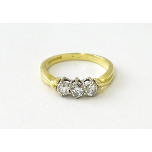 862 - An 18ct gold ring set with a trio of diamonds. Ring size approx. K 1/2