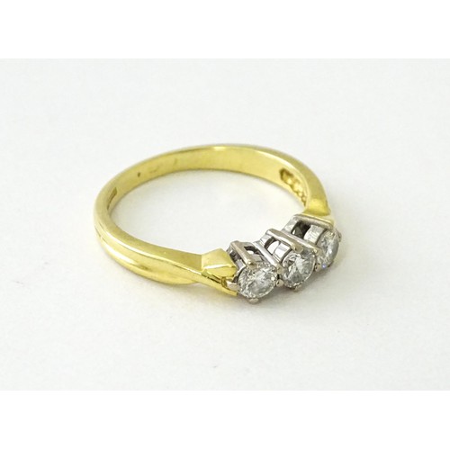 862 - An 18ct gold ring set with a trio of diamonds. Ring size approx. K 1/2