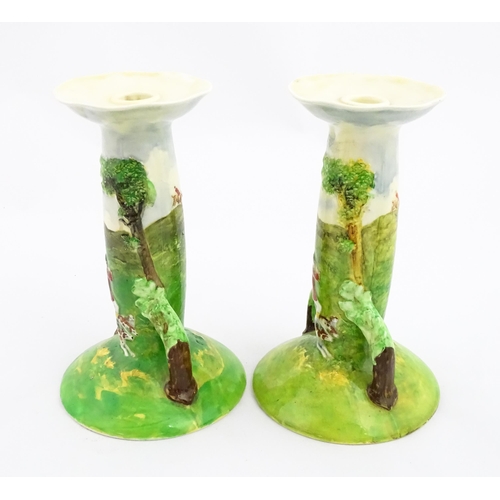 143 - A pair of Royal Doulton candlesticks of Art Nouveau form, decorated with hand painted fox hunting sc... 