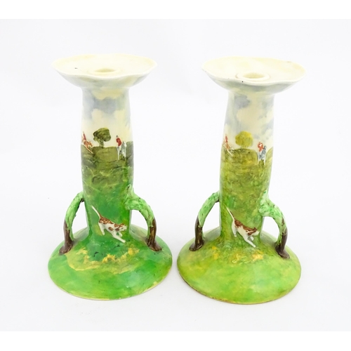 143 - A pair of Royal Doulton candlesticks of Art Nouveau form, decorated with hand painted fox hunting sc... 