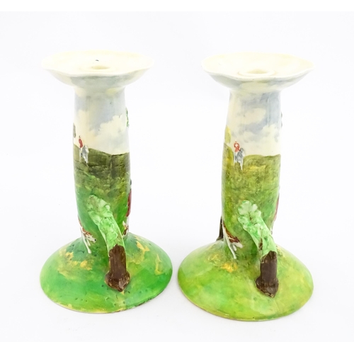 143 - A pair of Royal Doulton candlesticks of Art Nouveau form, decorated with hand painted fox hunting sc... 