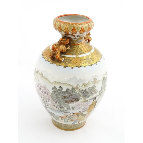 27 - A Japanese Satsuma vase with twin foo dog handles decorated with figures in an extensive landscape. ... 