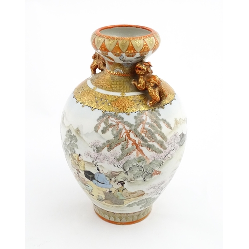 27 - A Japanese Satsuma vase with twin foo dog handles decorated with figures in an extensive landscape. ... 