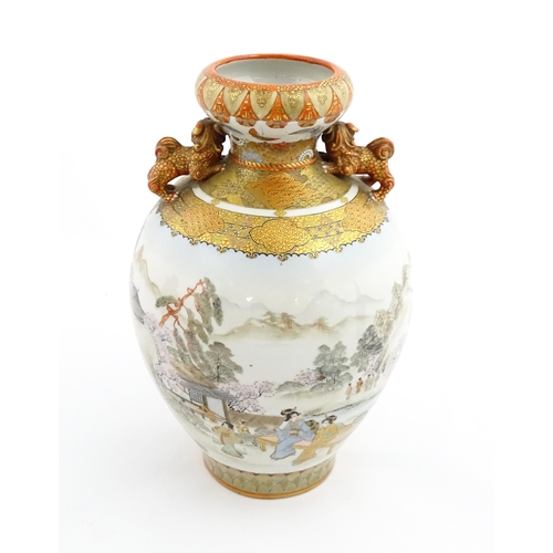 27 - A Japanese Satsuma vase with twin foo dog handles decorated with figures in an extensive landscape. ... 