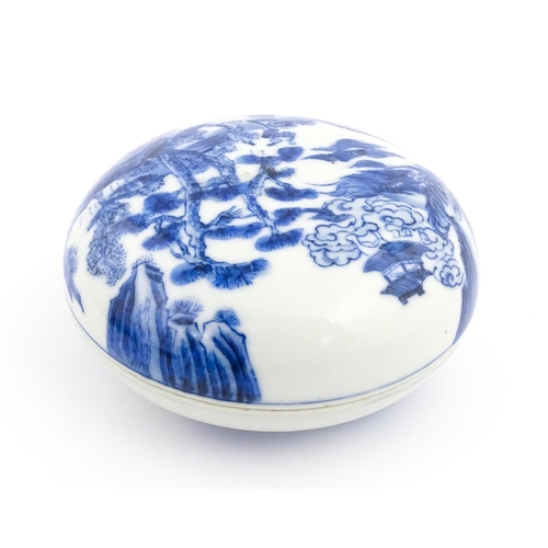 33 - A Chinese blue and white ink box of circular form decorated with figures in a landscape scene with a... 