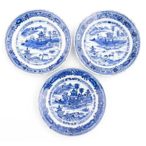 41 - Three Chinese blue and white plates, each decorated with a river landscape with pagoda style buildin... 