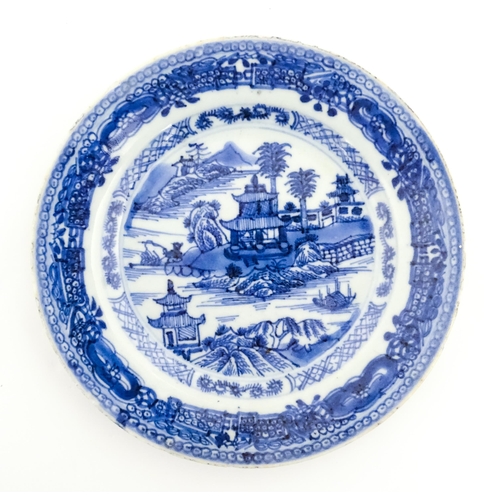 41 - Three Chinese blue and white plates, each decorated with a river landscape with pagoda style buildin... 