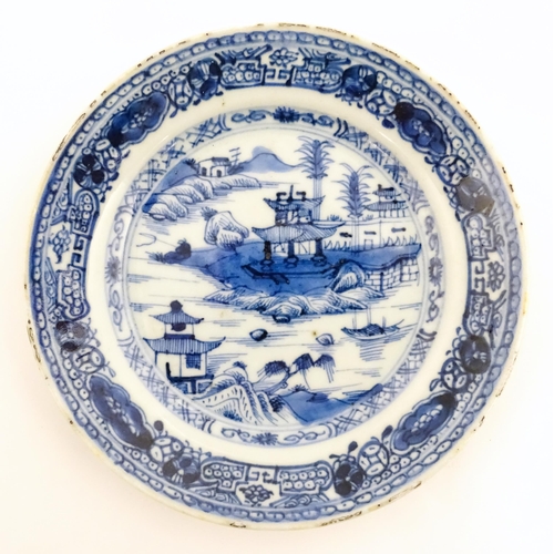 41 - Three Chinese blue and white plates, each decorated with a river landscape with pagoda style buildin... 