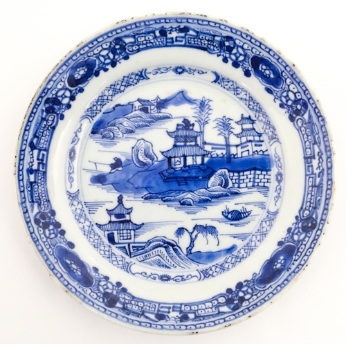 41 - Three Chinese blue and white plates, each decorated with a river landscape with pagoda style buildin... 