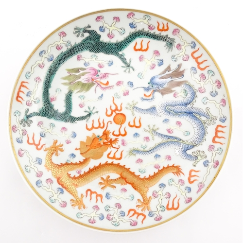 49 - A Chinese famille rose plate decorated with three dragons and a flaming pearl of wisdom. The reverse... 