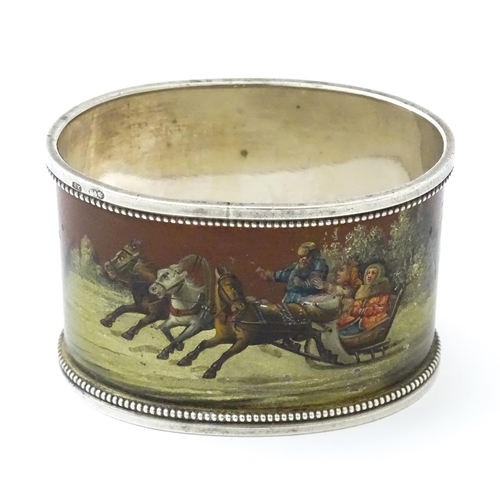 347 - A Russian silver napkin ring with lacquered and hand painted decoration depicting figures in a troik... 