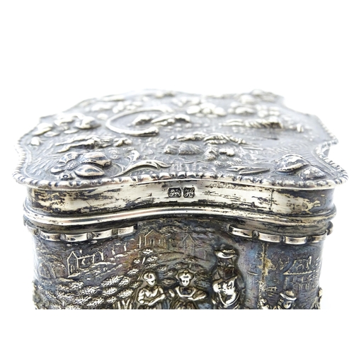 374 - An early 20thC silver jewellery box with embossed decoration depicting figures in landscape with hou... 