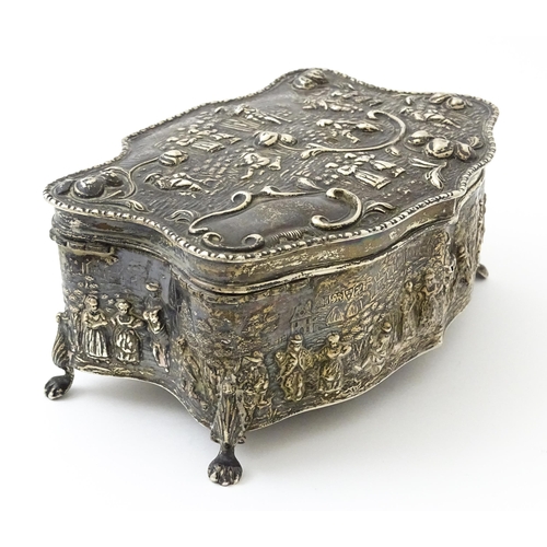 374 - An early 20thC silver jewellery box with embossed decoration depicting figures in landscape with hou... 