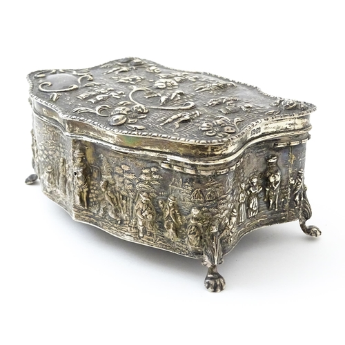 374 - An early 20thC silver jewellery box with embossed decoration depicting figures in landscape with hou... 