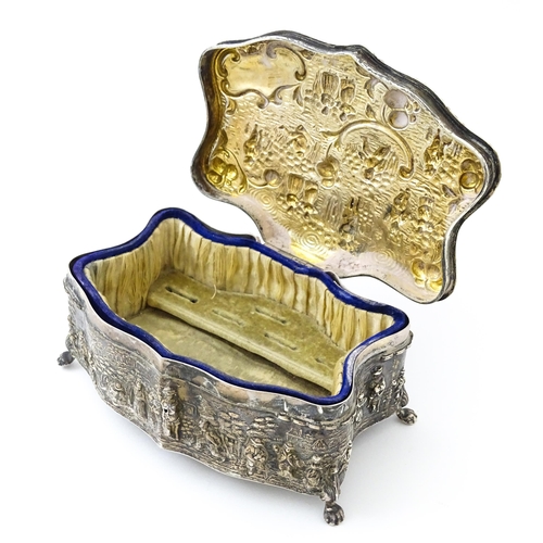 374 - An early 20thC silver jewellery box with embossed decoration depicting figures in landscape with hou... 