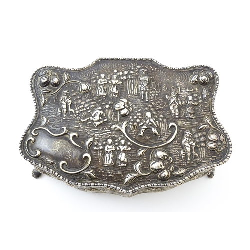 374 - An early 20thC silver jewellery box with embossed decoration depicting figures in landscape with hou... 