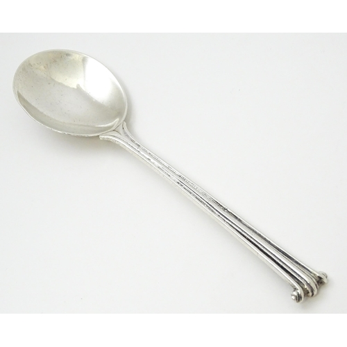 389 - Leslie G Durbin: A modern silver spoon with reeded handle and scroll finial, rat tail, and hammered ... 