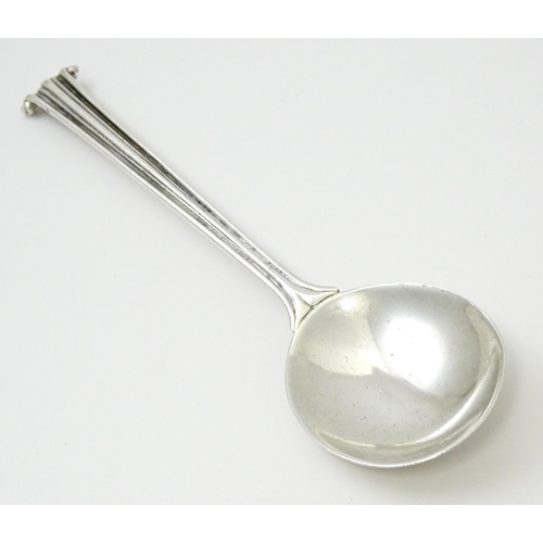 389 - Leslie G Durbin: A modern silver spoon with reeded handle and scroll finial, rat tail, and hammered ... 