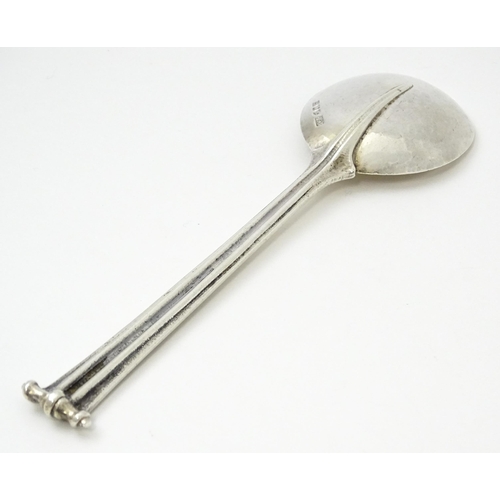 389 - Leslie G Durbin: A modern silver spoon with reeded handle and scroll finial, rat tail, and hammered ... 