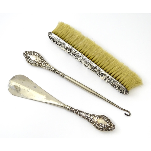 461 - A silver button hook and shoe horn, hallmarked Chester 1910. Together with a silver mounted brush ha... 