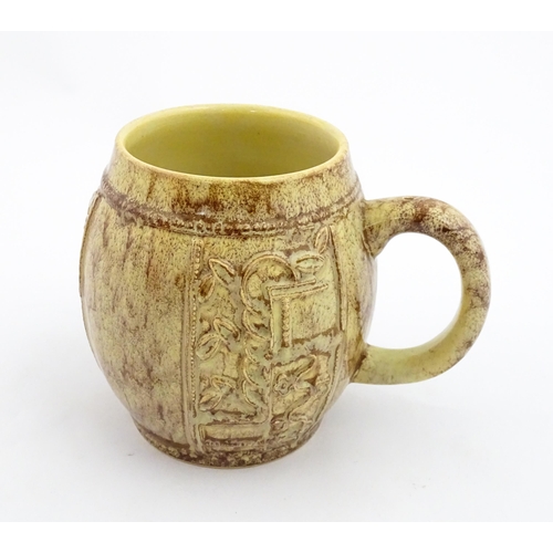 109 - A 20thC mug / tankard of bulbous form with mottled brown glaze and relief floral decoration. Marked ... 