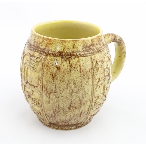 109 - A 20thC mug / tankard of bulbous form with mottled brown glaze and relief floral decoration. Marked ... 