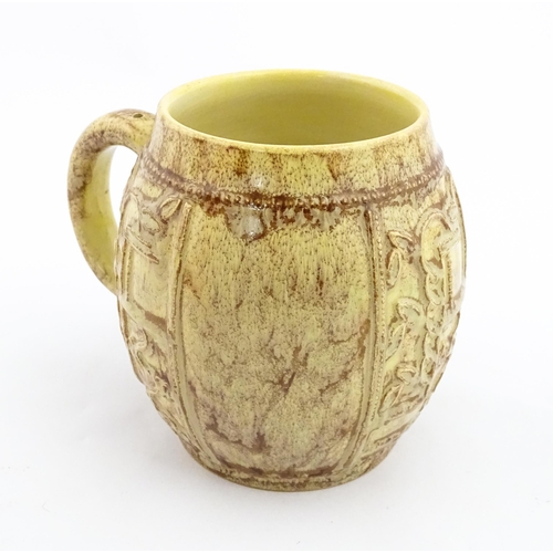 109 - A 20thC mug / tankard of bulbous form with mottled brown glaze and relief floral decoration. Marked ... 