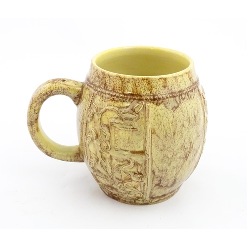 109 - A 20thC mug / tankard of bulbous form with mottled brown glaze and relief floral decoration. Marked ... 