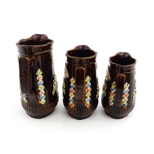 229 - A graduated set of three Victorian Measham bargeware jugs, each bearing a plaque titled A Present to... 