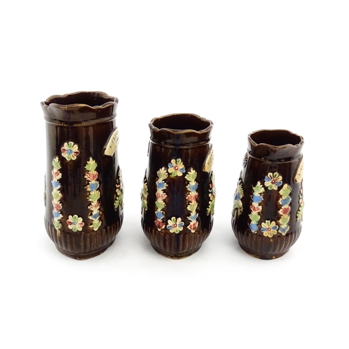 229 - A graduated set of three Victorian Measham bargeware jugs, each bearing a plaque titled A Present to... 