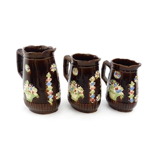 229 - A graduated set of three Victorian Measham bargeware jugs, each bearing a plaque titled A Present to... 