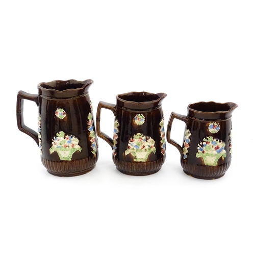 229 - A graduated set of three Victorian Measham bargeware jugs, each bearing a plaque titled A Present to... 