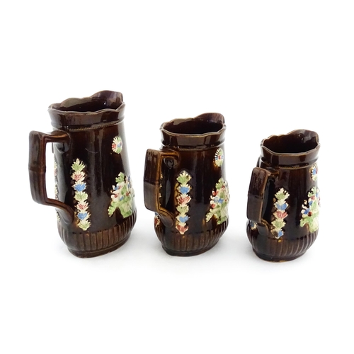 229 - A graduated set of three Victorian Measham bargeware jugs, each bearing a plaque titled A Present to... 