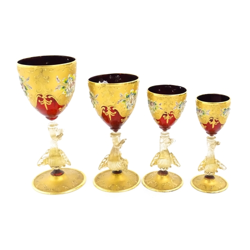 313 - A set of four graduated ruby glass and gilt goblets with dolphin formed stems. Largest approx. 7 1/2... 