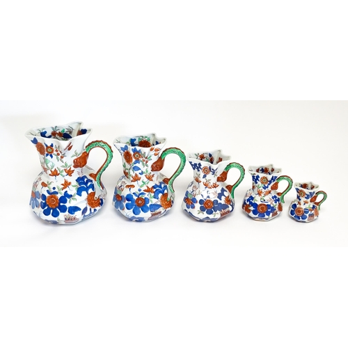 184 - A graduated set of five ironstone china jugs with floral and foliate decoration. Marked under. Large... 