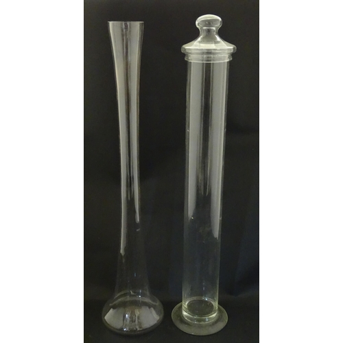 342 - A clear glass storage jar of elongated form with associated lid, together with a tall clear glass va... 