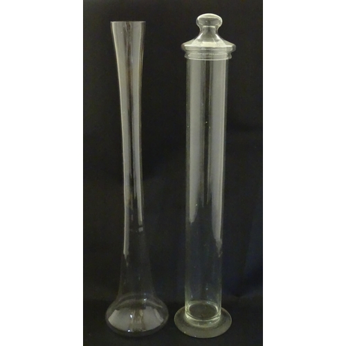 342 - A clear glass storage jar of elongated form with associated lid, together with a tall clear glass va... 