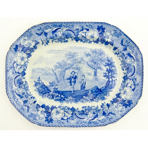 78 - A blue and white meat plate decorated in the Rural Scenery pattern with two figures in a country lan... 