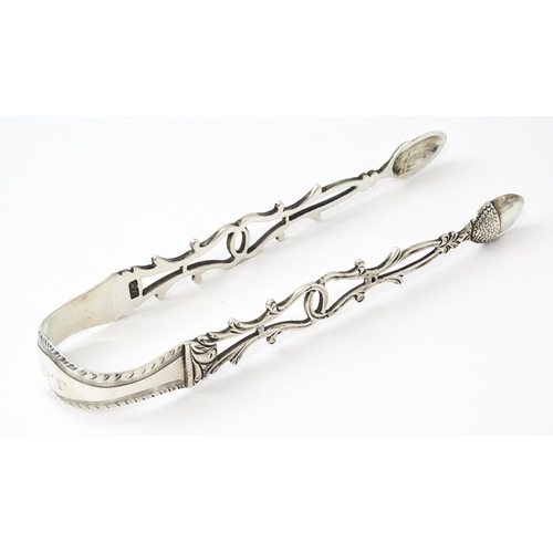 424 - 18thC silver sugar tongs with openwork decoration and acorn grips, maker W.C. Approx. 5 1/2