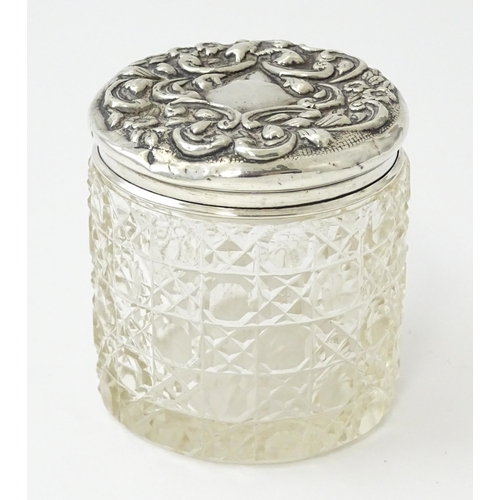 438 - A cut glass dressing table pot of cylindrical form with embossed silver lid hallmarked Birmingham 19... 