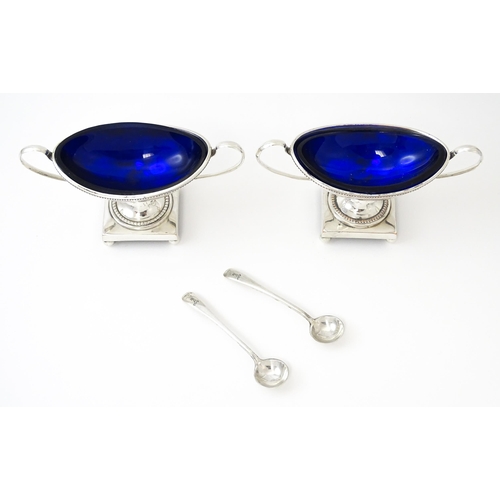 439 - A pair of silver plate twin handled pedestal salts of urn form, with blue glass liners. Together wit... 