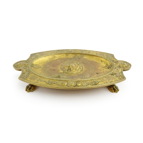 1210 - A 19thC French gilt brass dish / stand of shaped form raised on four lion paw feet, decorated with l... 