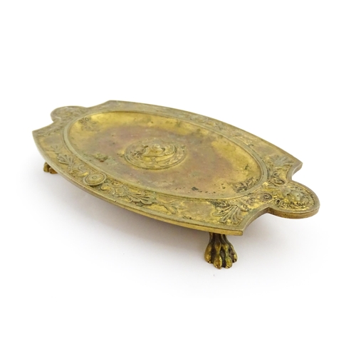 1210 - A 19thC French gilt brass dish / stand of shaped form raised on four lion paw feet, decorated with l... 