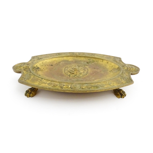 1210 - A 19thC French gilt brass dish / stand of shaped form raised on four lion paw feet, decorated with l... 