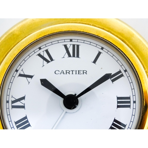 1658 - A Cartier brass cased alarm clock with quartz movement, the white dial with Roman numerals and signe... 