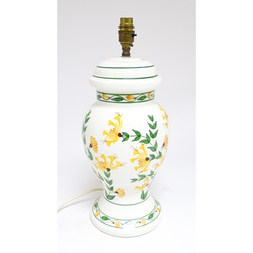 1676 - A late 20thC ceramic table lamp the white ground decorated with yellow and green floral decoration. ... 